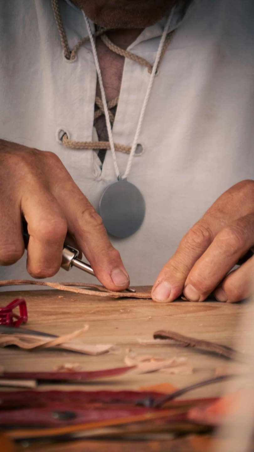 Artigiano al lavoro su cuoio in un laboratorio.
